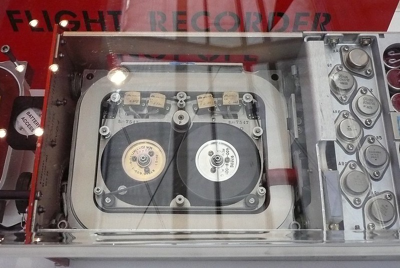 A museum display showing an open metal box with reels, pulleys and wires