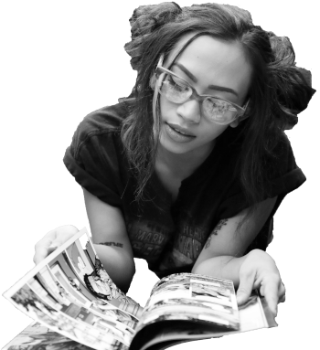 A teenage girl crouches on the floor reading a comic book