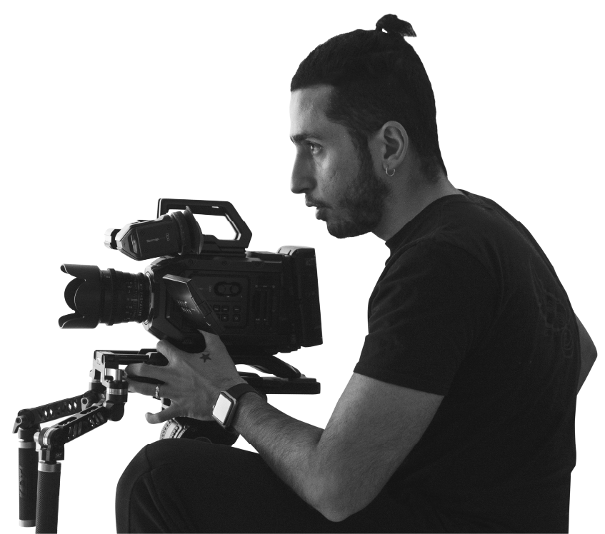 A man with his hair in a bun operating a video camera